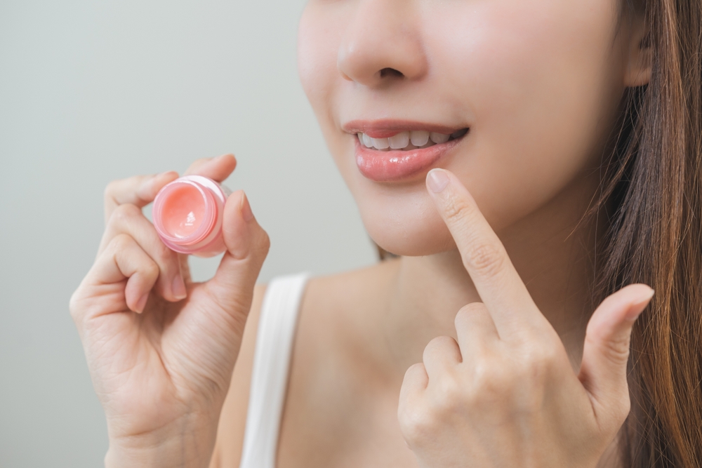 ผู้หญิงกำลังทาลิปทำให้ปากอวบอิ่ม